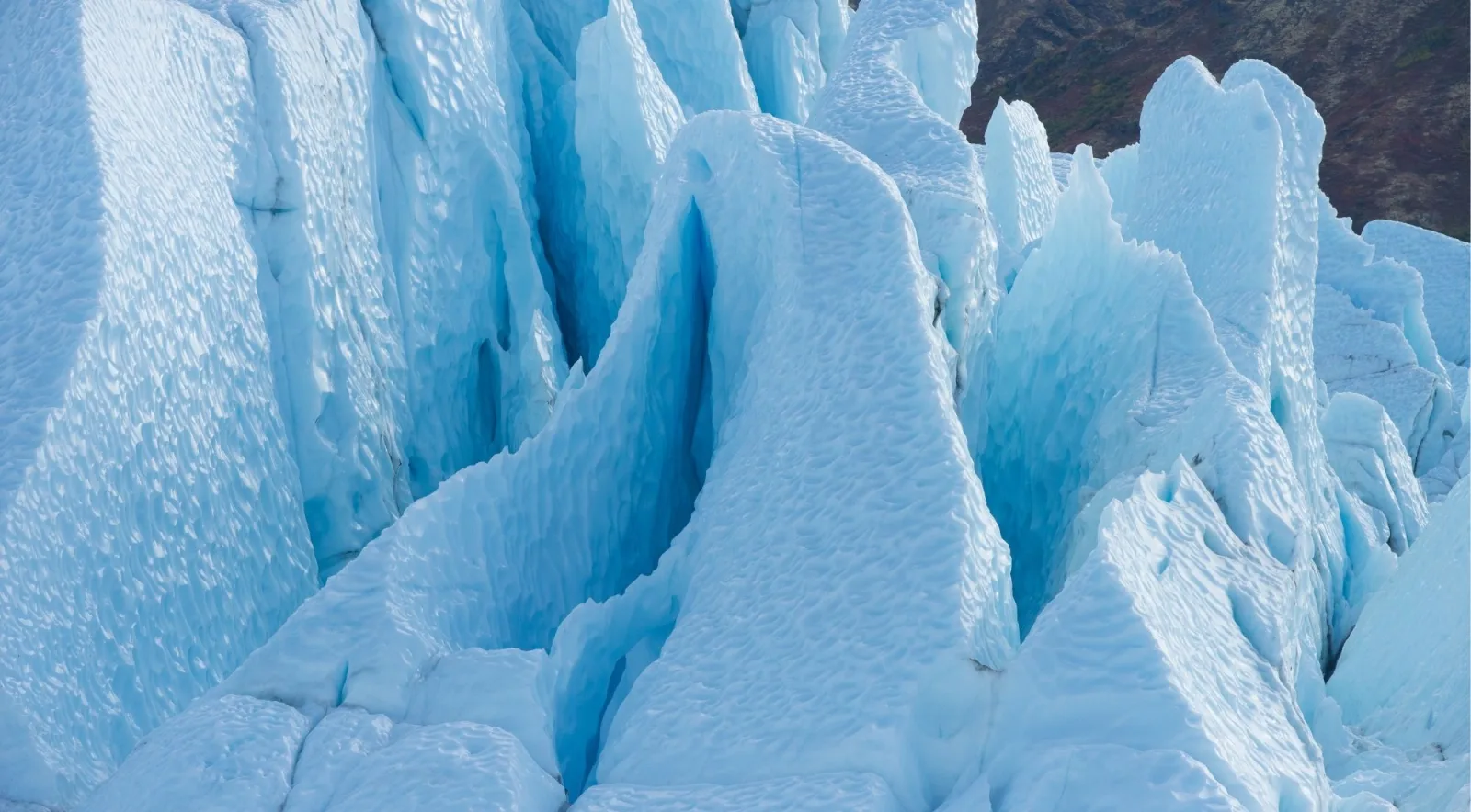 Close view of pale blue serac towers with a bare tundra slope behind