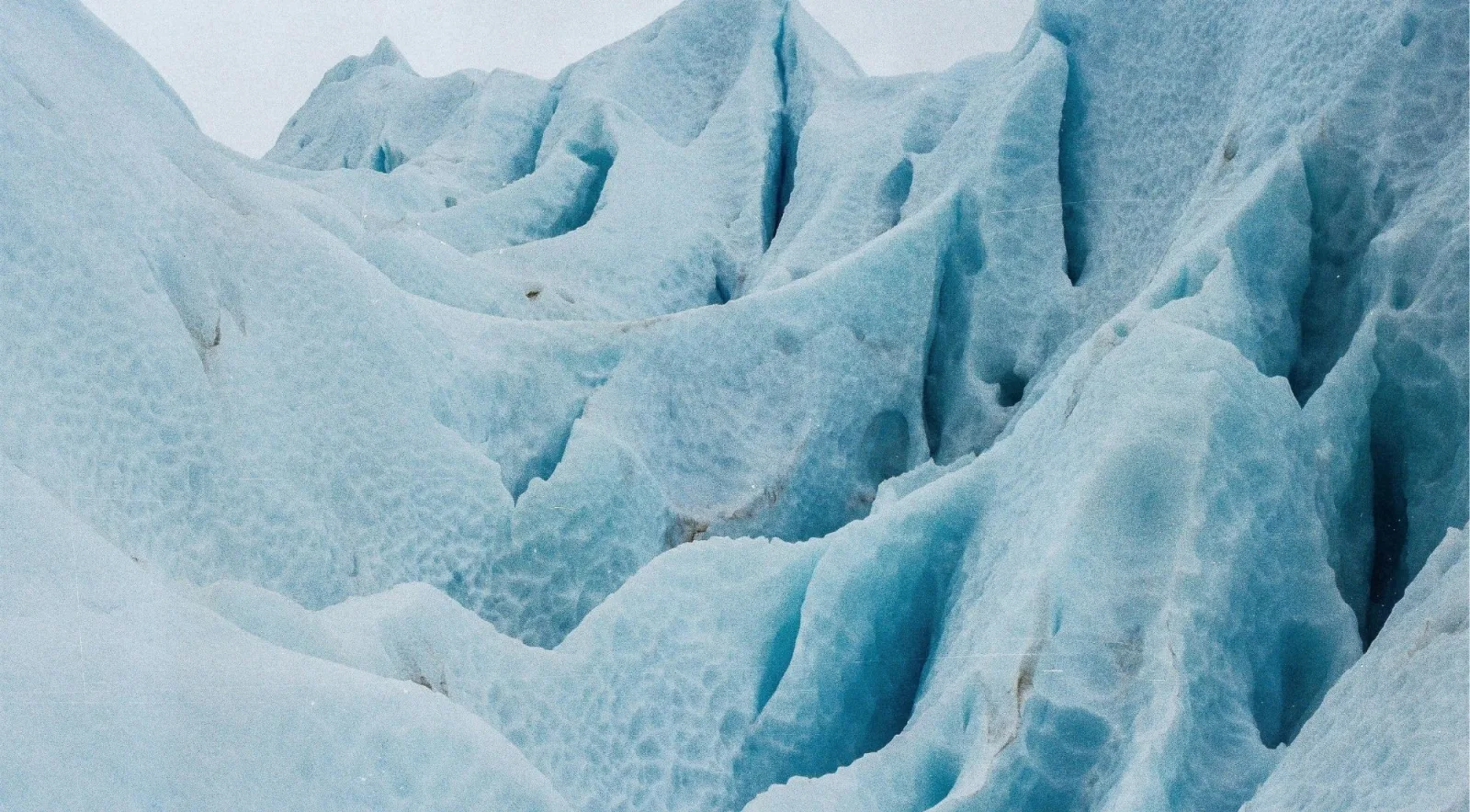 Ridges and hollows of blue glacier ice in flat overcast light