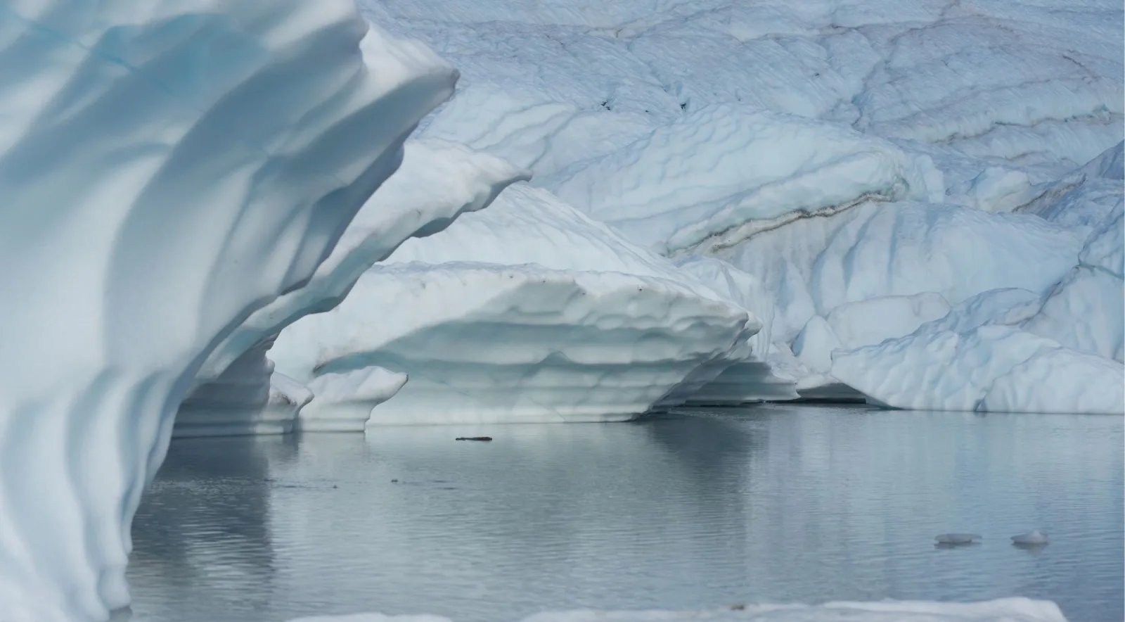 Sculpted ice forms mirrored in the calm surface of a glacial pool