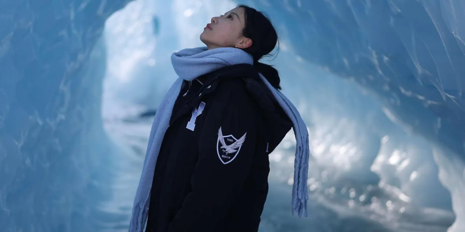 Visitor looking up inside a blue-walled ice tunnel on the glacier