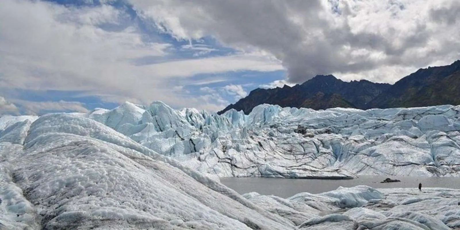 The glacier's broad snow-covered surface under a heavy winter sky