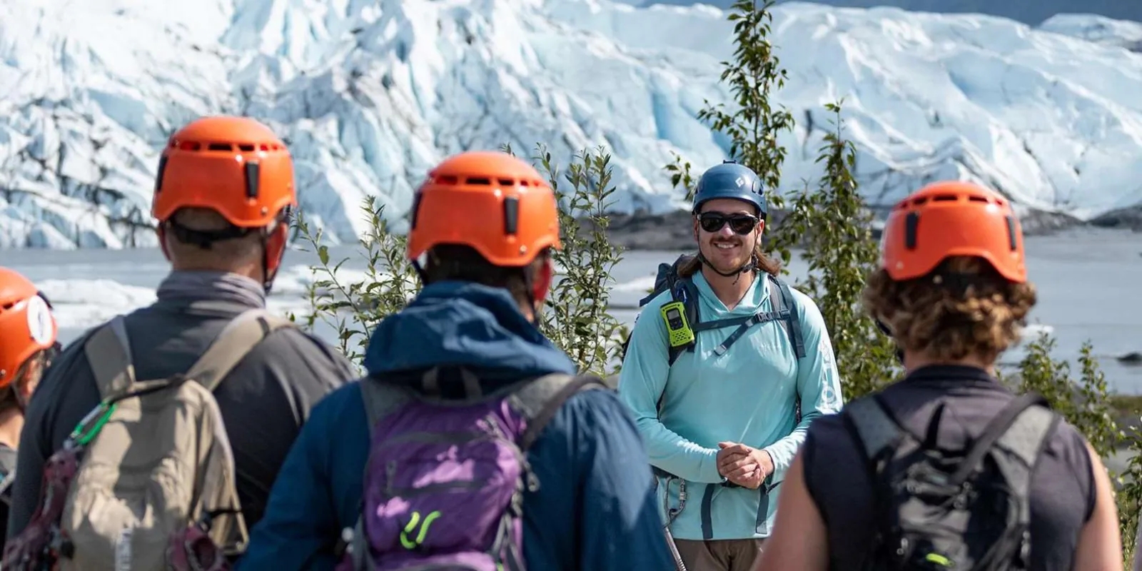 Glacier guide in sunglasses briefing helmeted hikers before the walk onto the ice