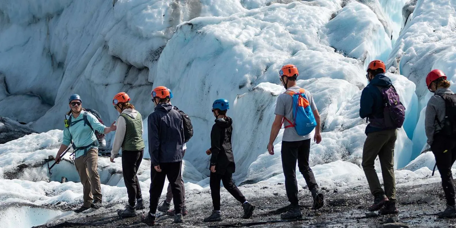Group crossing bare glacier ice beneath towering blue seracs