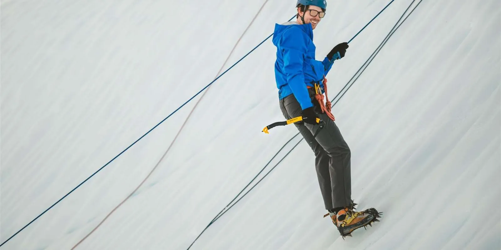 Climber front-pointing up a vertical ice wall on a top rope