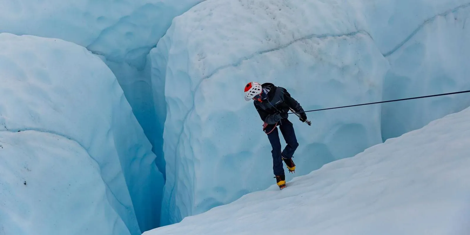 Climber lowering off on a rope beside a blue ice fin