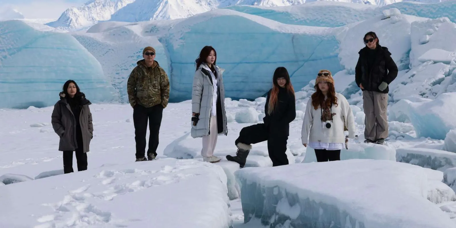 Visitors standing among snow-covered blocks of glacier ice