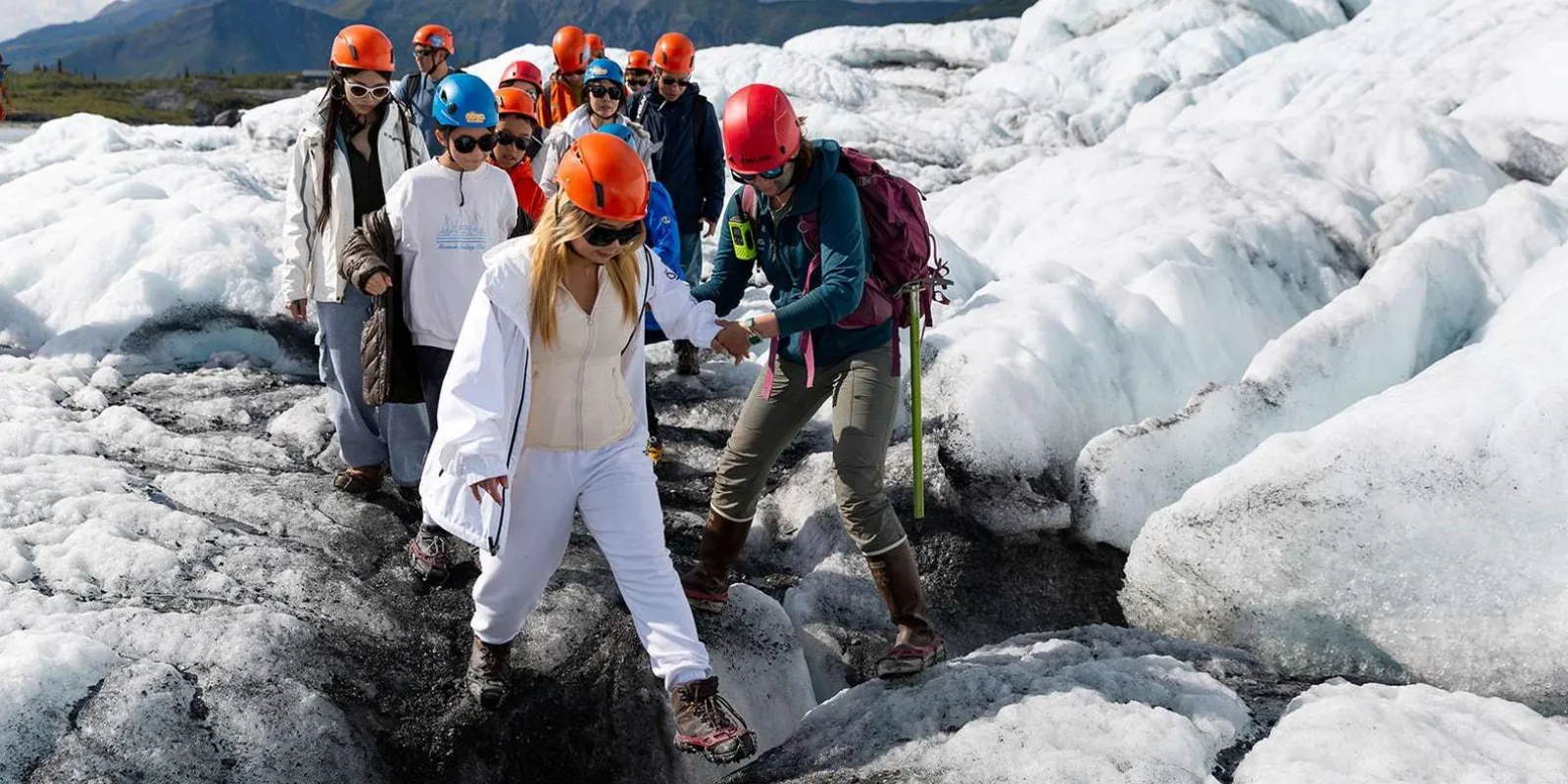 Family group picking their way down a ridge of glacier ice